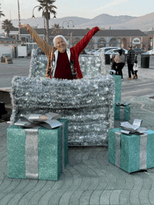 a woman in a red sweater is standing in a box with her arms up