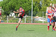 a soccer player wearing a red jersey that says ' aegon ' on it is kicking the ball