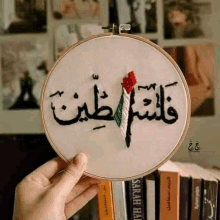 a person is holding an embroidery hoop with arabic writing