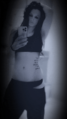 a woman taking a picture of herself with a tattoo on her stomach