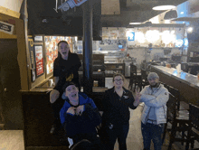 a group of people posing for a picture in a restaurant with a sign on the wall that says " no smoking "