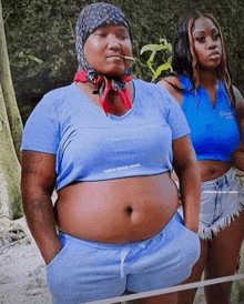 a woman with a bandana on her head is smoking a cigarette while standing next to another woman