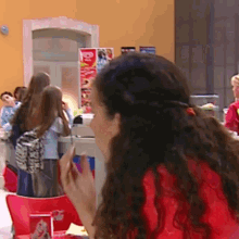 a woman in a red shirt is sitting at a table in front of a sign that says coca cola