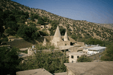 a building in the middle of a valley with trees and mountains in the background