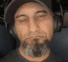 a man with a beard and hat is wearing headphones .