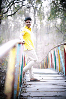 a man in a yellow shirt is standing on a bridge with the name manish roy below him