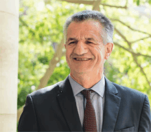 a man in a suit and tie is smiling and looking at the camera