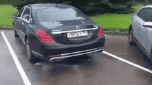 a black mercedes is parked in a parking lot next to a silver car .