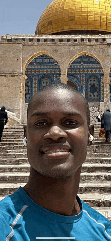 a man in a blue shirt smiles in front of a dome