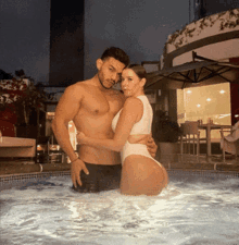 a man and a woman are posing for a picture in a pool at night