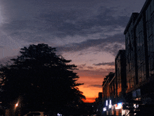 a sunset over a city street with a building that says ' a ' on the front