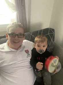 a boy wearing a bds shirt sits on a couch with another boy