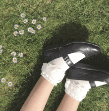 a person wearing black shoes and white socks is laying in the grass with daisies