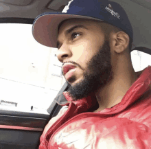 a man with a beard wears a dodgers hat and a red jacket