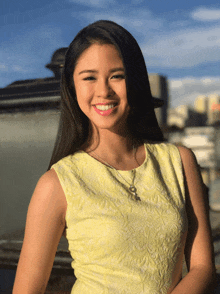 a woman in a yellow dress smiles for a picture