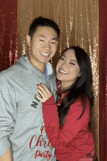 a man and woman are posing for a picture and the man is wearing a christmas party sweatshirt