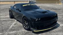 a black dodge challenger is parked in a parking lot with a banner on the windshield that says boosted lucket