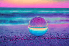 a colorful glass ball on a beach with a rainbow reflection of the ocean