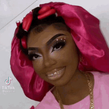 a woman wearing a pink satin hat and a pink shirt is smiling