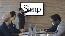 a man in a suit is giving a presentation in front of a screen that says simp