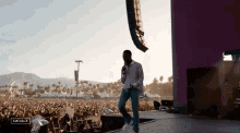 a man stands on a stage with a microphone in front of a crowd at a music festival and the word coachella is visible