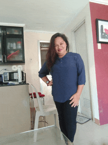 a woman in a blue shirt is standing in front of a white chair