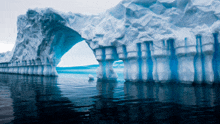 a large iceberg in the ocean with a blue arch