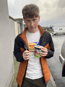 a young man holding a spoon and a container of ben & jerry 's