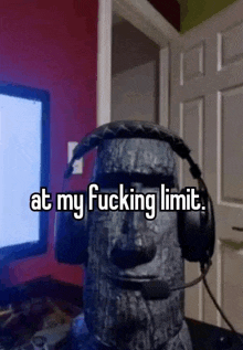 a statue of a moai wearing headphones is sitting in front of a computer .