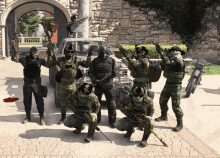 a group of soldiers posing for a picture with a car behind them