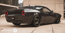 a black dodge challenger is parked in front of a building