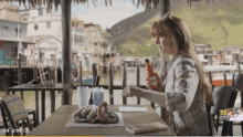 a woman sits at a table with a bottle of ketchup