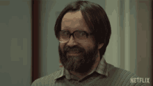 a man with glasses and a beard is smiling in front of a netflix ad