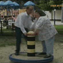 a man and a woman are playing on a merry go round in a park with omn music written on the bottom