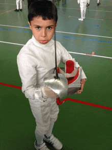 a young boy in a fencing uniform holds a sword