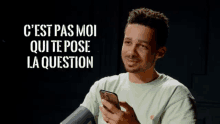 a man holding a cell phone with the words " c est pas moi qui te pose la question " above him