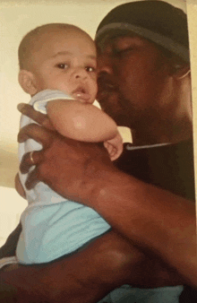 a man is holding a baby in his arms and kissing it