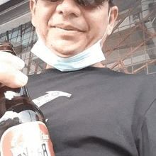 a man wearing a mask and sunglasses is holding a beer bottle .