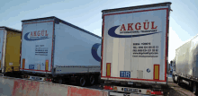 two trucks from akgul international transport are parked on the side of a road