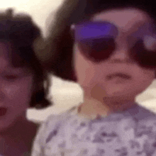 two children wearing sunglasses are standing next to each other and making funny faces .