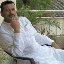 a man is sitting in a chair on a balcony with a palm tree in the background .