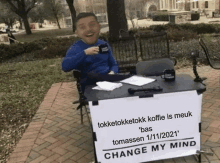 a man sitting at a table with a change my mind sign