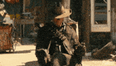 a man in a cowboy hat sits in a chair with a fallout logo in the background