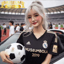 a woman holding a soccer ball wearing a black adidas museumbola 2019 jersey