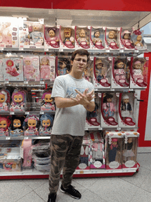 a man wearing a shirt that says olympic games stands in front of a shelf of dolls