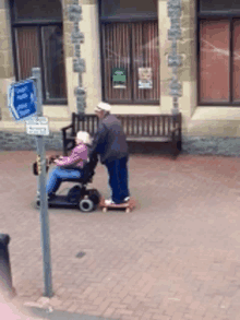 a man pushes a woman in a wheelchair on a skateboard