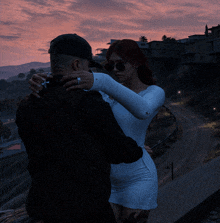 a man and a woman are hugging in front of a pink sky