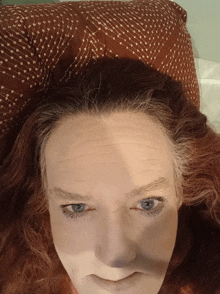 a woman with red hair and blue eyes is laying on a bed