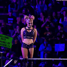 a woman in a crop top and shorts stands in front of a crowd with a sign that says texas 3:16