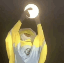 a person in a yellow jacket is holding a light in their hand